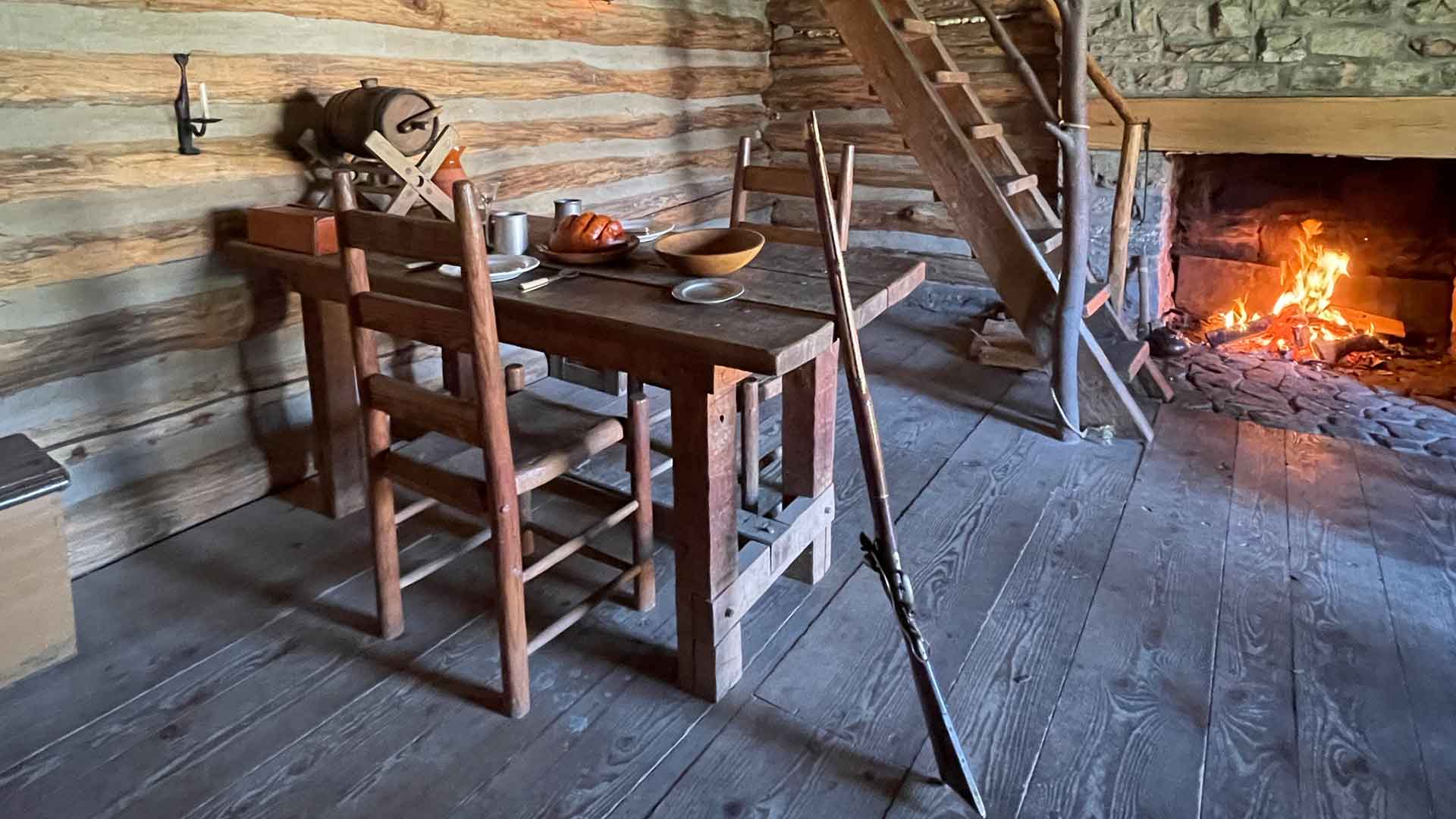 a dining table and fireplace inside the officers quarters at Fort Roberdeau 